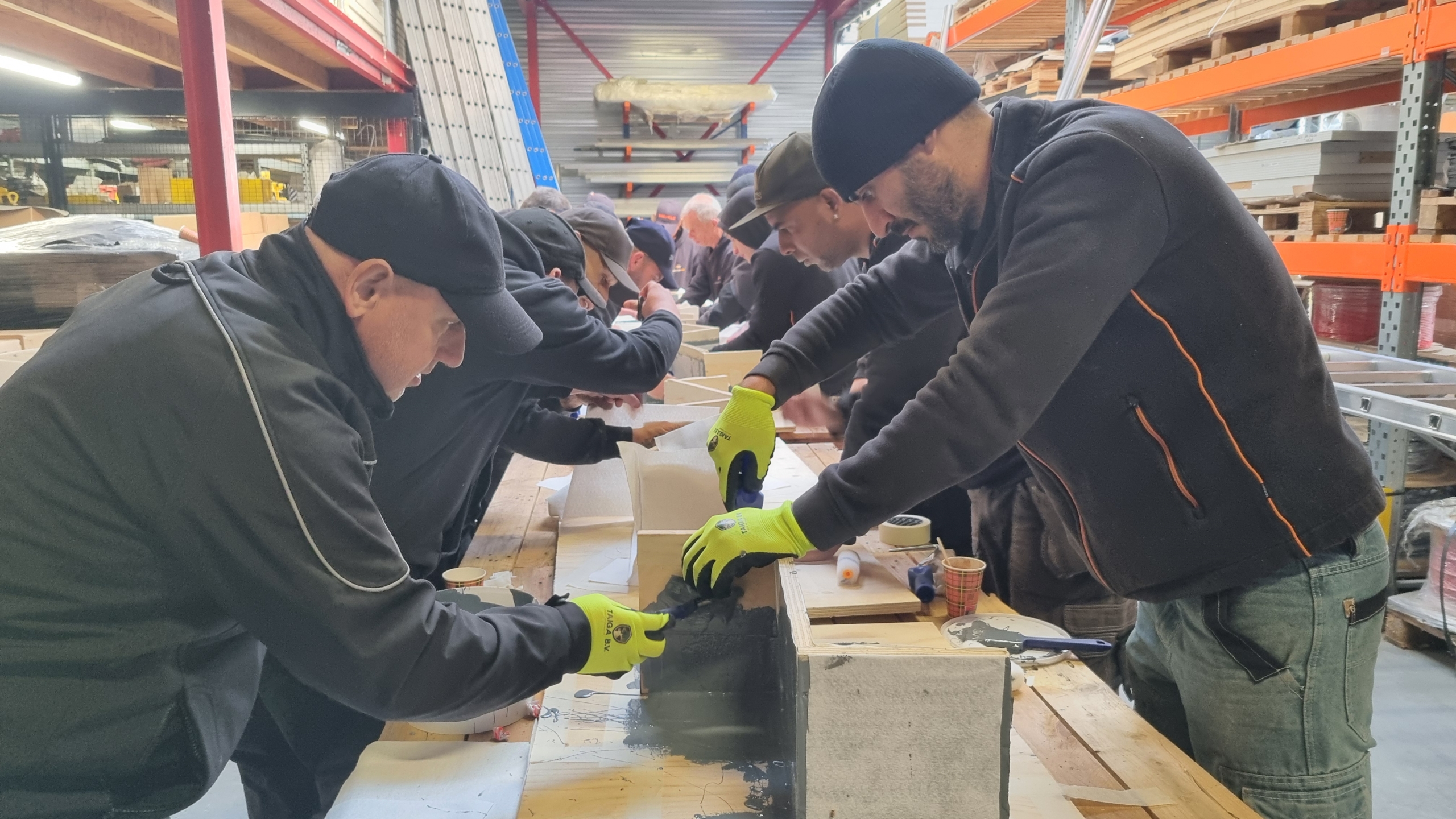 Vaklieden met handschoenen brengen SOLIDPROOF SMP aan op oefenblokken tijdens een producttraining op locatie.