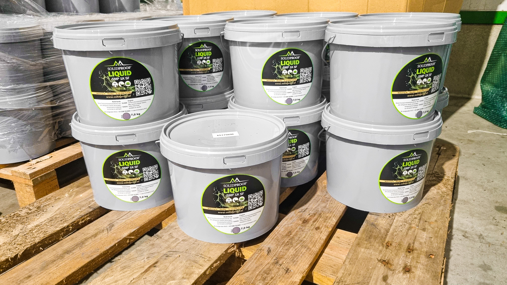 Grijze emmers SOLIDPROOF Liquid SMP 1K SF van 7 kg gestapeld op een houten pallet in het magazijn.
