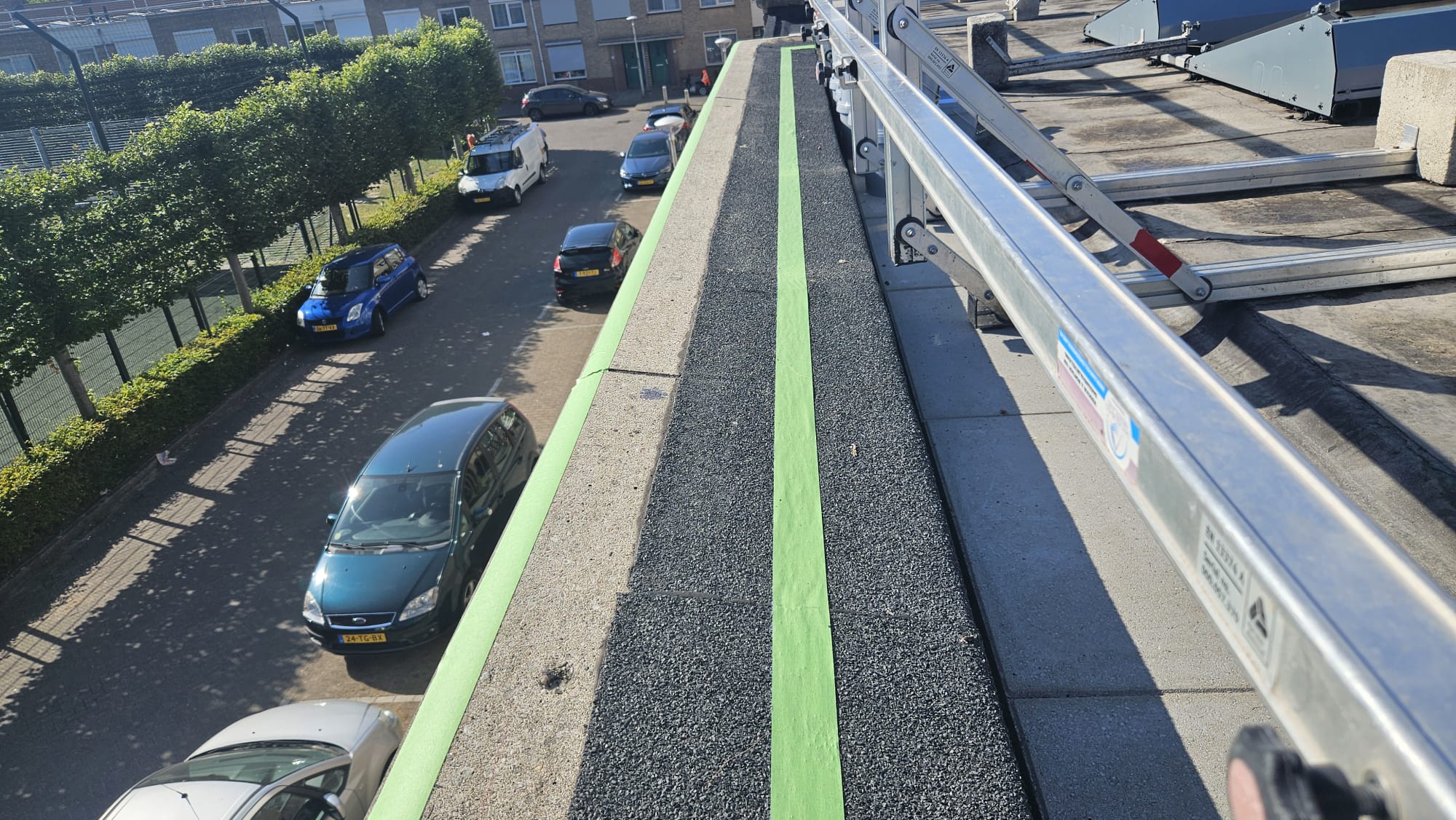 Dakrand met valbeveiliging, afgeplakt met groene tape voor het aanbrengen van een vloeibare afdichting.